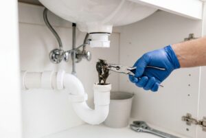 Plumber removing hair and debris buildup causing recurring drain clogs from a bathroom sink pipe
